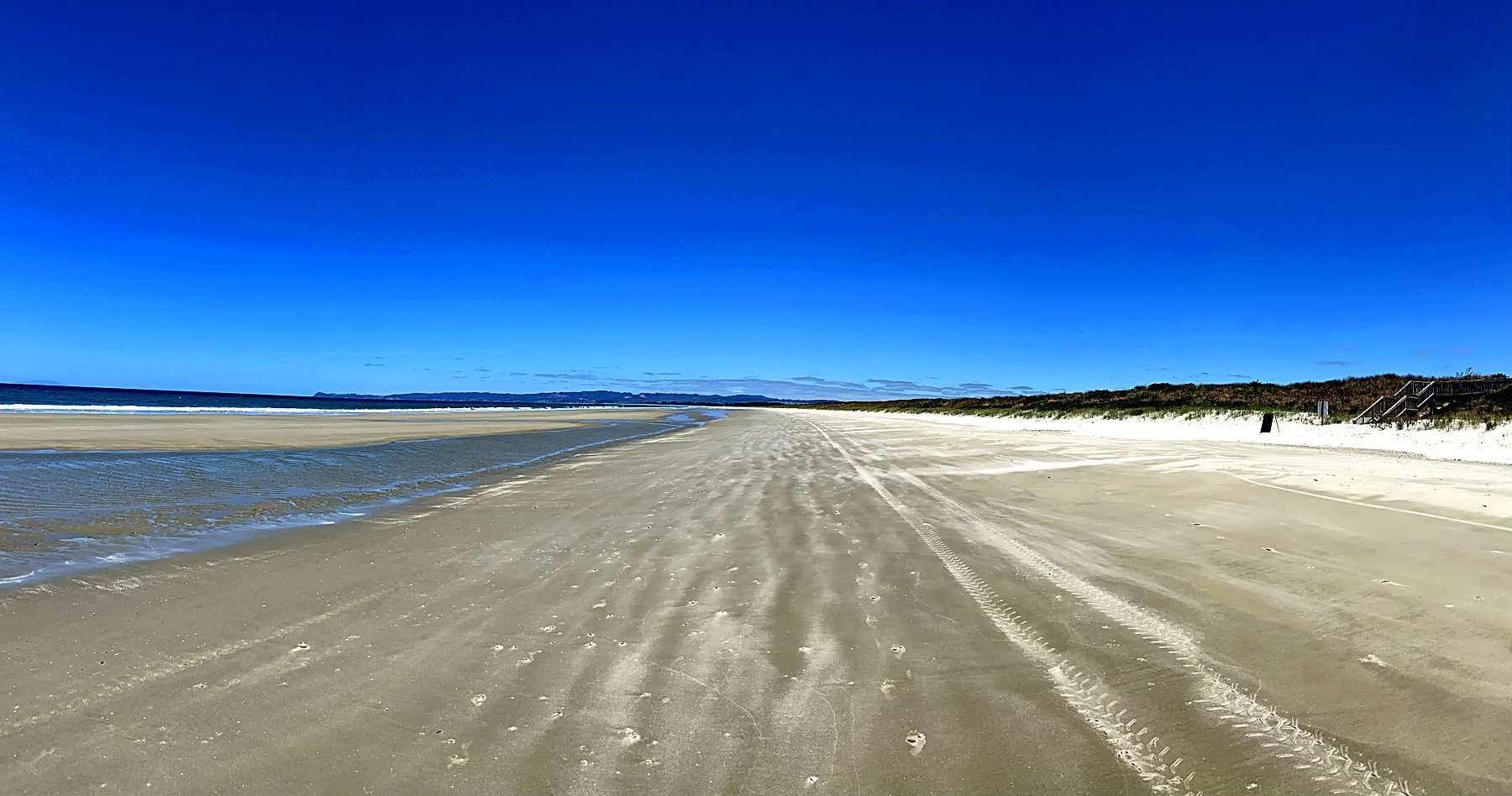 Low tide at Ruakākā Beach, firm sand running south towards Waipu